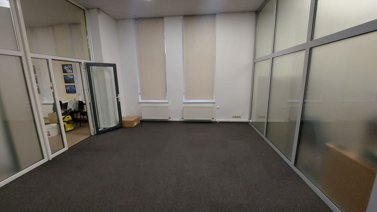 Atjaunotā biroja telpa ar baltām sienām un jaunām paklājflīzēm