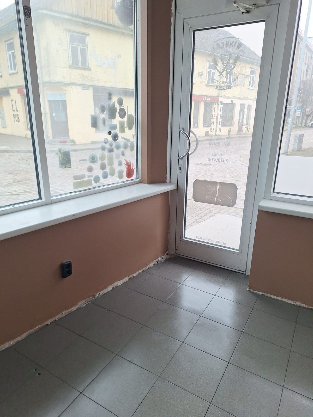 Kafejnīcas telpa pēc remonta ar siltos toņos nokrāsotām sienām un skatlogu uz ielu