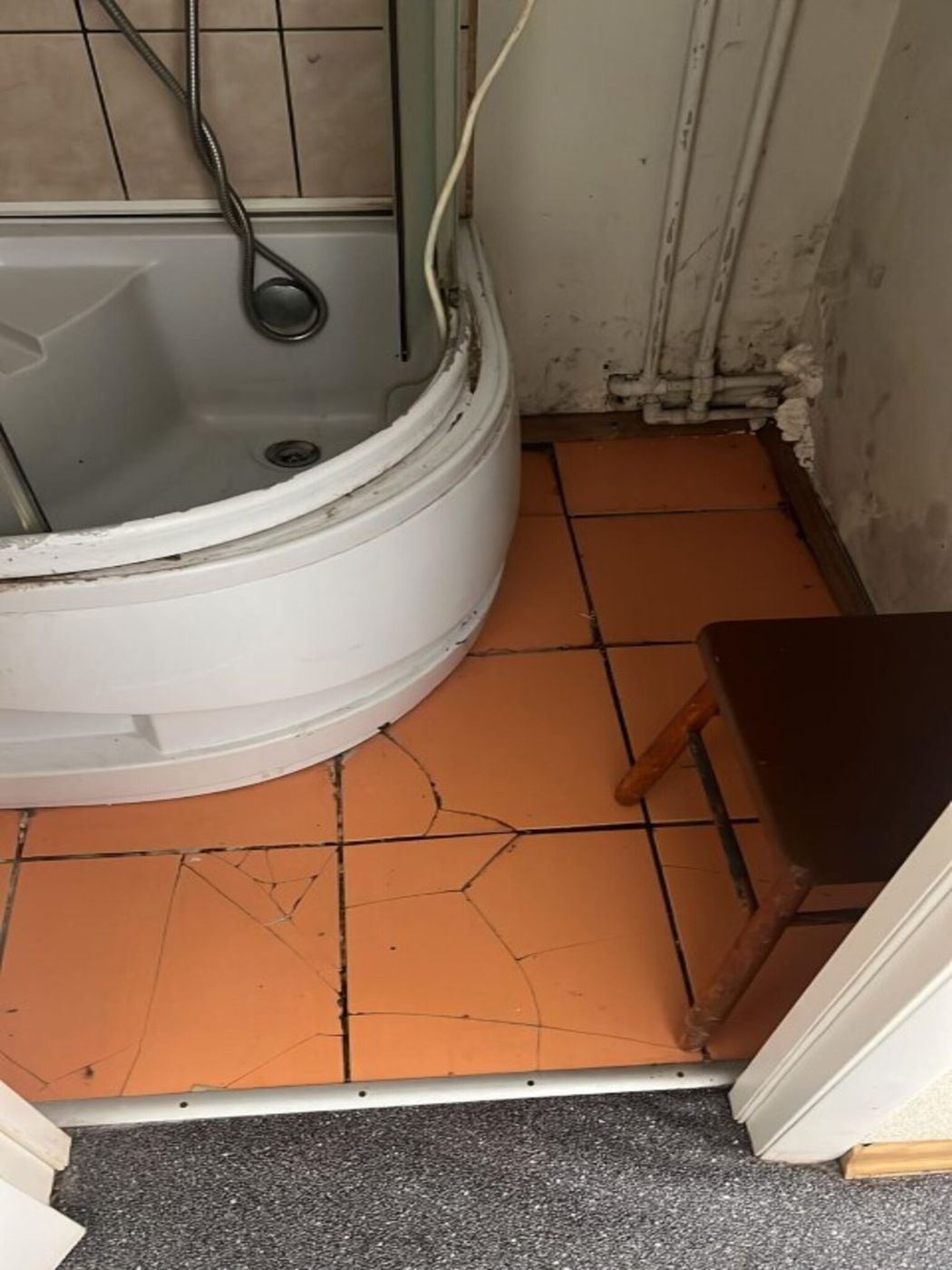 Veca dušas kabīne un saplaisājušas grīdas flīzes